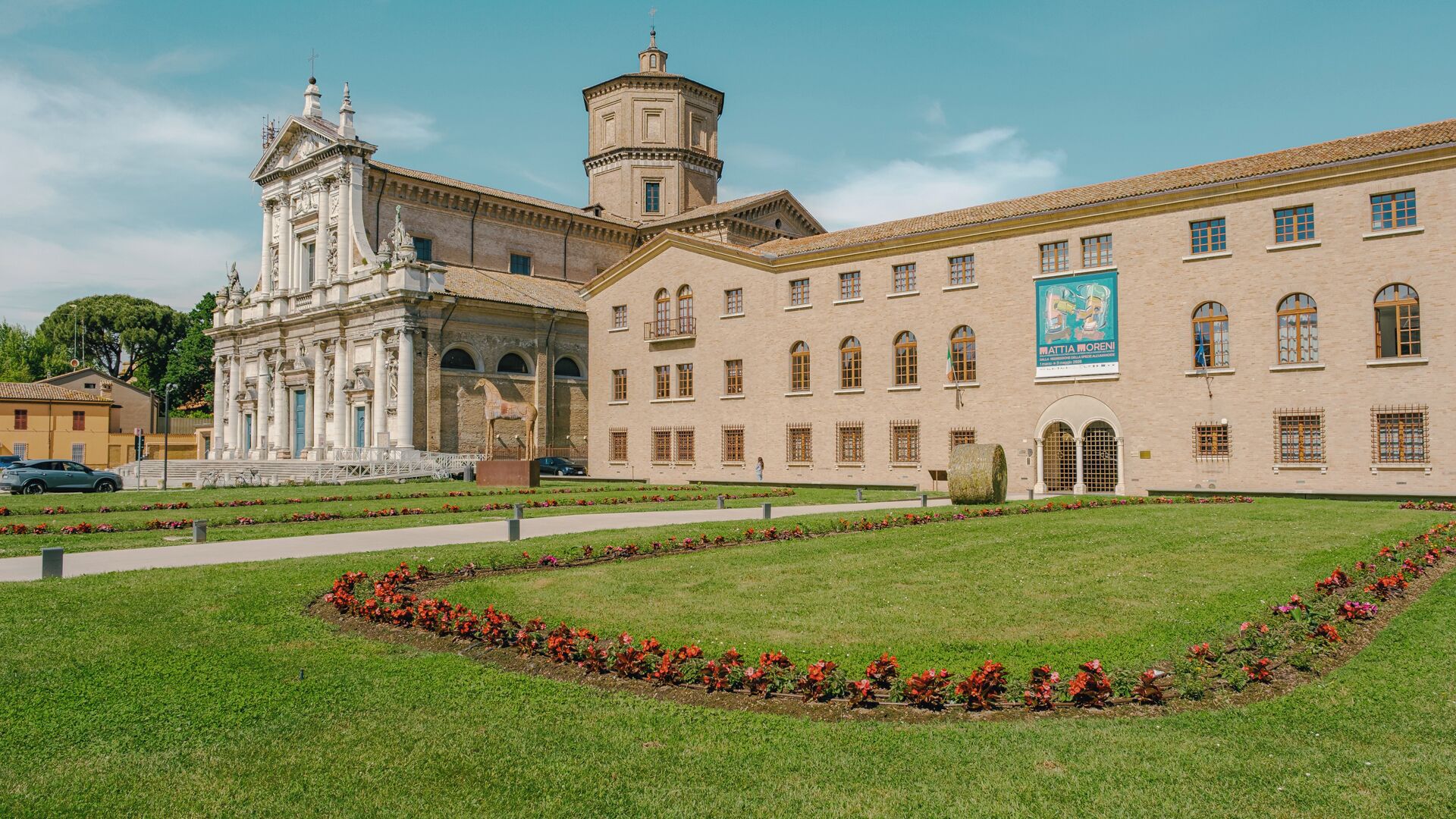 A historic building with classical architecture, a central courtyard with a statue, and a banner on the facade.