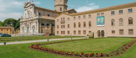 A historic building with classical architecture, a central courtyard with a statue, and a banner on the facade.