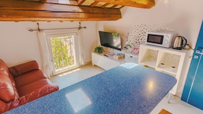 A cozy room with a brown leather sofa, a TV, a microwave, and a coffee maker. - Domus Dantis Paolo e Francesca (Ravenna)