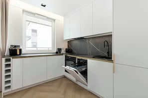 Eine moderne Küche mit weißen Schränken, einem eingebauten Backofen und einem Fenster über der Spüle.