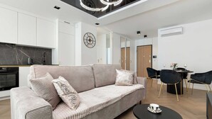 Un salon moderne comprenant un canapé, une table à manger avec des chaises, un coin cuisine et un luminaire au plafond.