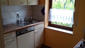 A kitchen with a sink, dishwasher, and window with a view of greenery. - Holiday Home 'Ferienhaus Für 4 Personen 50 M²' with Private Terrace and Private Garden (Egloffstein)