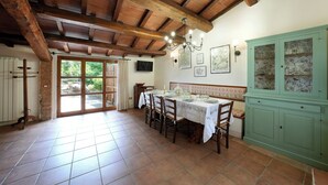 Un coin repas avec un plafond en bois, une table dressée pour quatre personnes et un buffet vert aux portes vitrées.