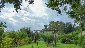 A garden with a wooden swing set and a grassy area. - Violetta Apartment near Lucca (Segromigno in Monte)