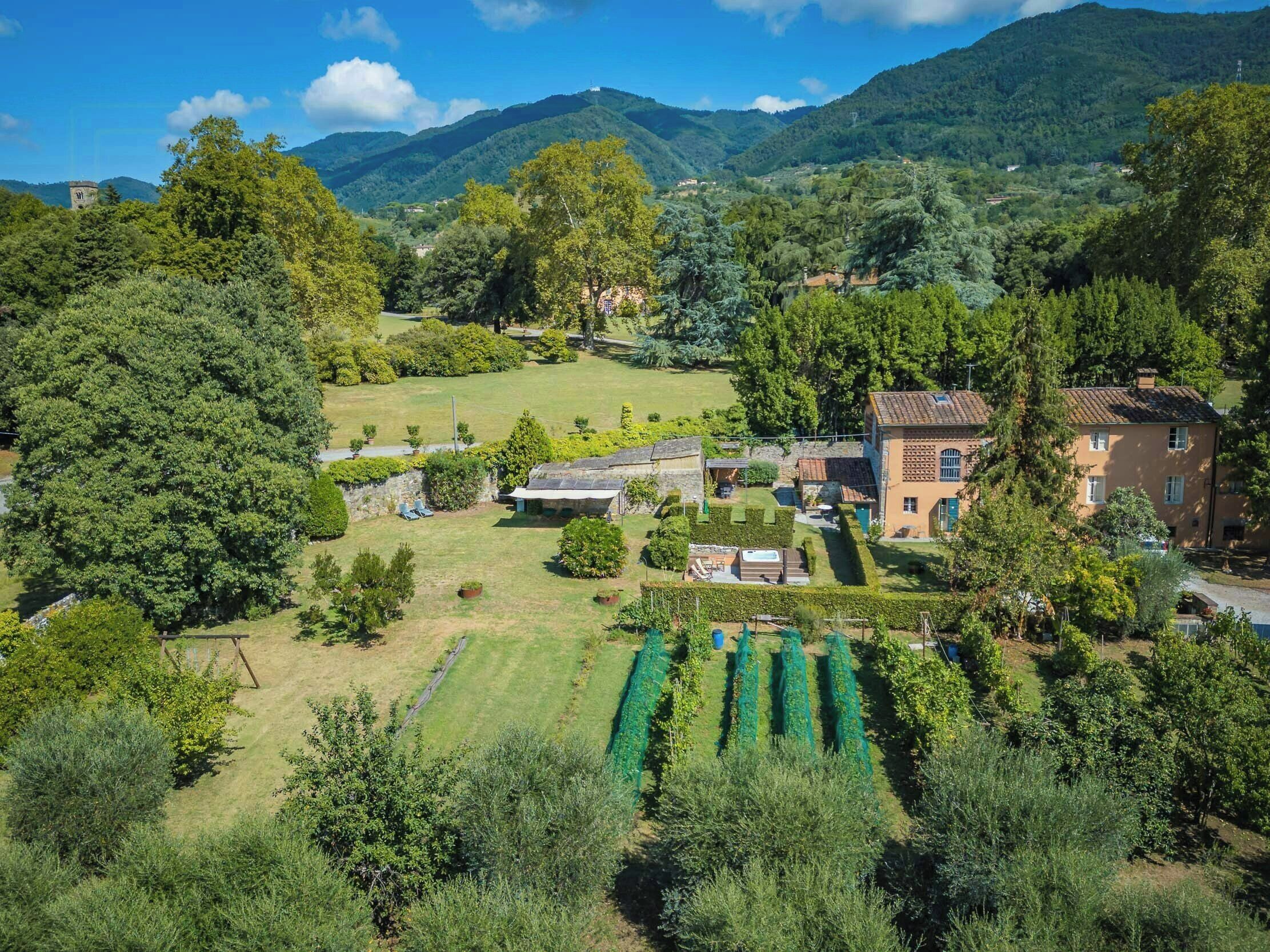 Una propiedad rural con una casa grande, un jardín y un viñedo.