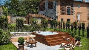 A house with a hot tub, outdoor seating, and a stone wall. - Violetta Apartment near Lucca (Segromigno in Monte)