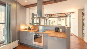 Uma cozinha moderna com forno embutido, coifa de aço inoxidável e bancadas de madeira.