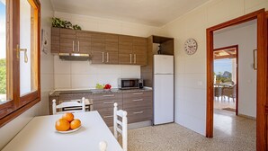 Eine Küche mit Holzausstattung, einem weißen Kühlschrank, einer Mikrowelle und einem Esstisch mit Orangen.