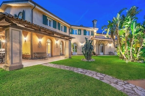 A large, two-story building with a patio area, outdoor seating, and a well-maintained lawn.