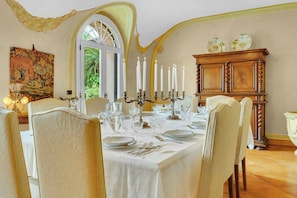 A dining room with a table set for six, a chandelier, and a large window.