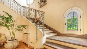 Un escalier avec une rampe en fer forgé, une plante en pot et une vue par la fenêtre.