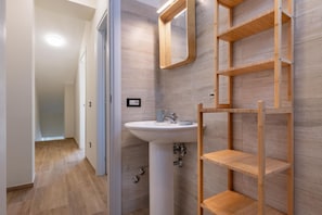 A bathroom with a pedestal sink, wooden shelves, and a mirror. - A comfortable 90 sqm apartment on two levels connected by an internal staircase, ideal for up to 6 people.The property is located in Torre Faro, one of the most picturesque towns in the Messina area, about 15 km from the center of Messina, at a point whe (Messina)
