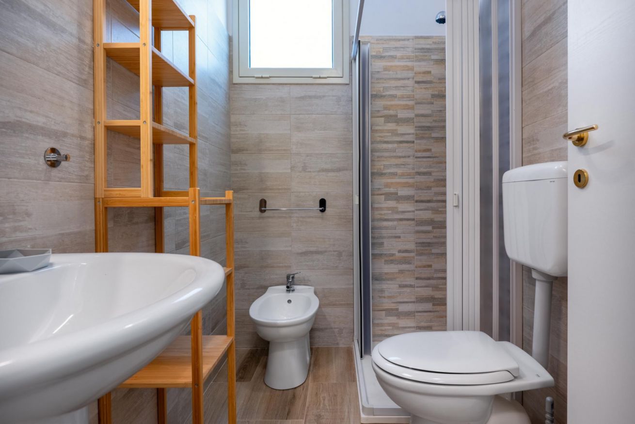 Een moderne badkamer met een groot wastafel, bidet, toilet en een douchecabine van glas.