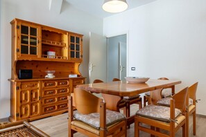 Un comedor con una mesa y sillas de madera, un aparador con cajones y una puerta que da a otra habitación.