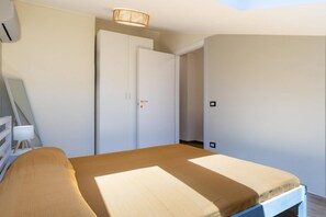 Un dormitorio con cama, armario, escritorio y silla.