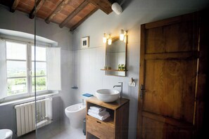 A bathroom with a large window, a white sink, a mirror, and a wooden cabinet. - Apartment with view in Segromigno in Monte (Segromigno in Monte)