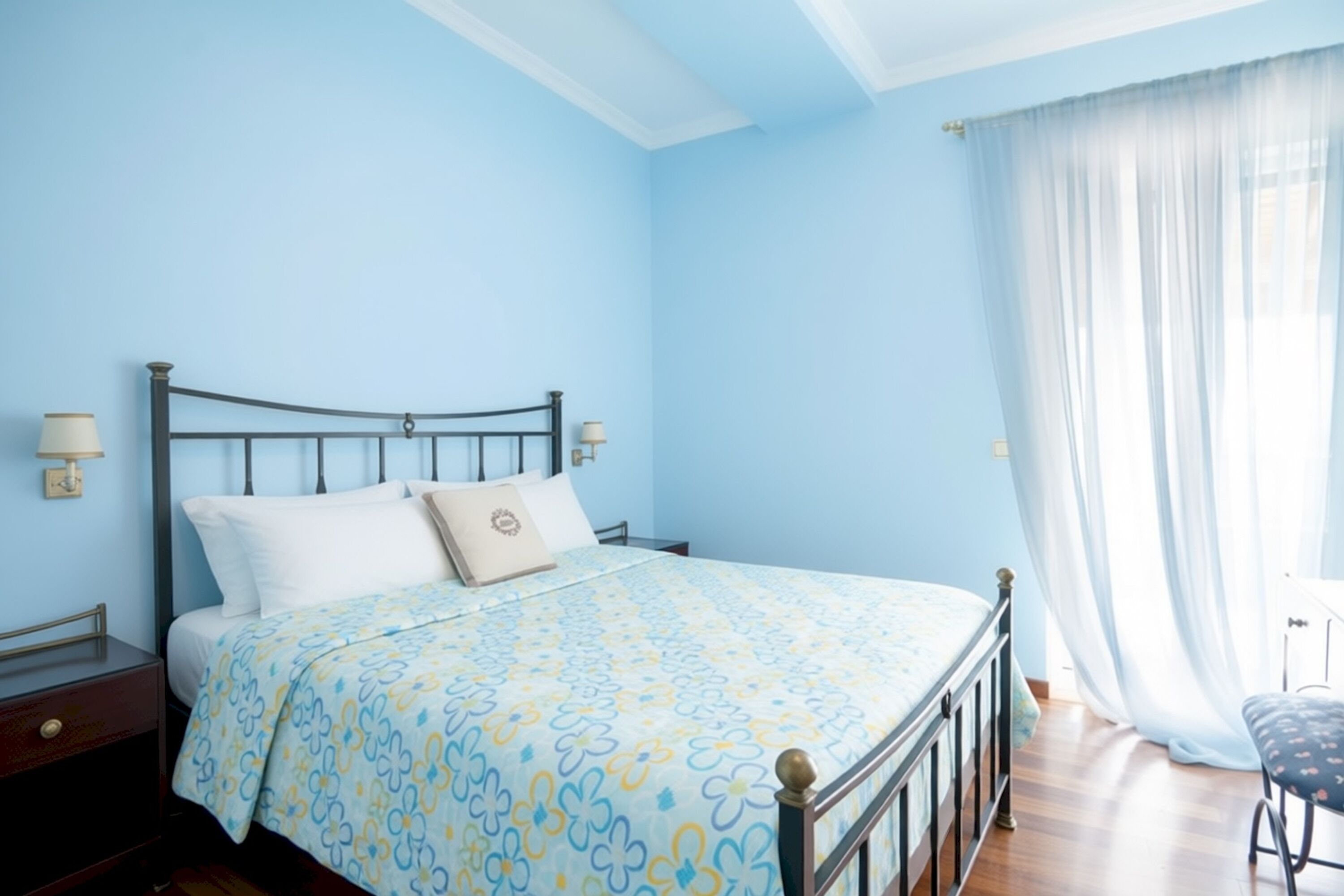 A bedroom with a bed, bedside tables, a window with curtains, and a chair.