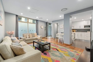 A modern living room with a sofa, coffee table, and a colorful rug. - Cityline Haven Harbourside Living with City Energy (Pyrmont)