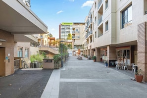 A courtyard with a central pathway, buildings with balconies, and outdoor seating. - Cityline Haven Harbourside Living with City Energy (Pyrmont)