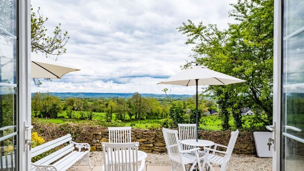 A patio with white furniture, including a bench and chairs, and a table. - Hilltop View by Escape Ordinary (Lisbellaw, Enniskillen)