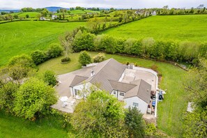 A large house with a spacious backyard, surrounded by lush green fields and trees. - Hilltop View by Escape Ordinary (Lisbellaw, Enniskillen)