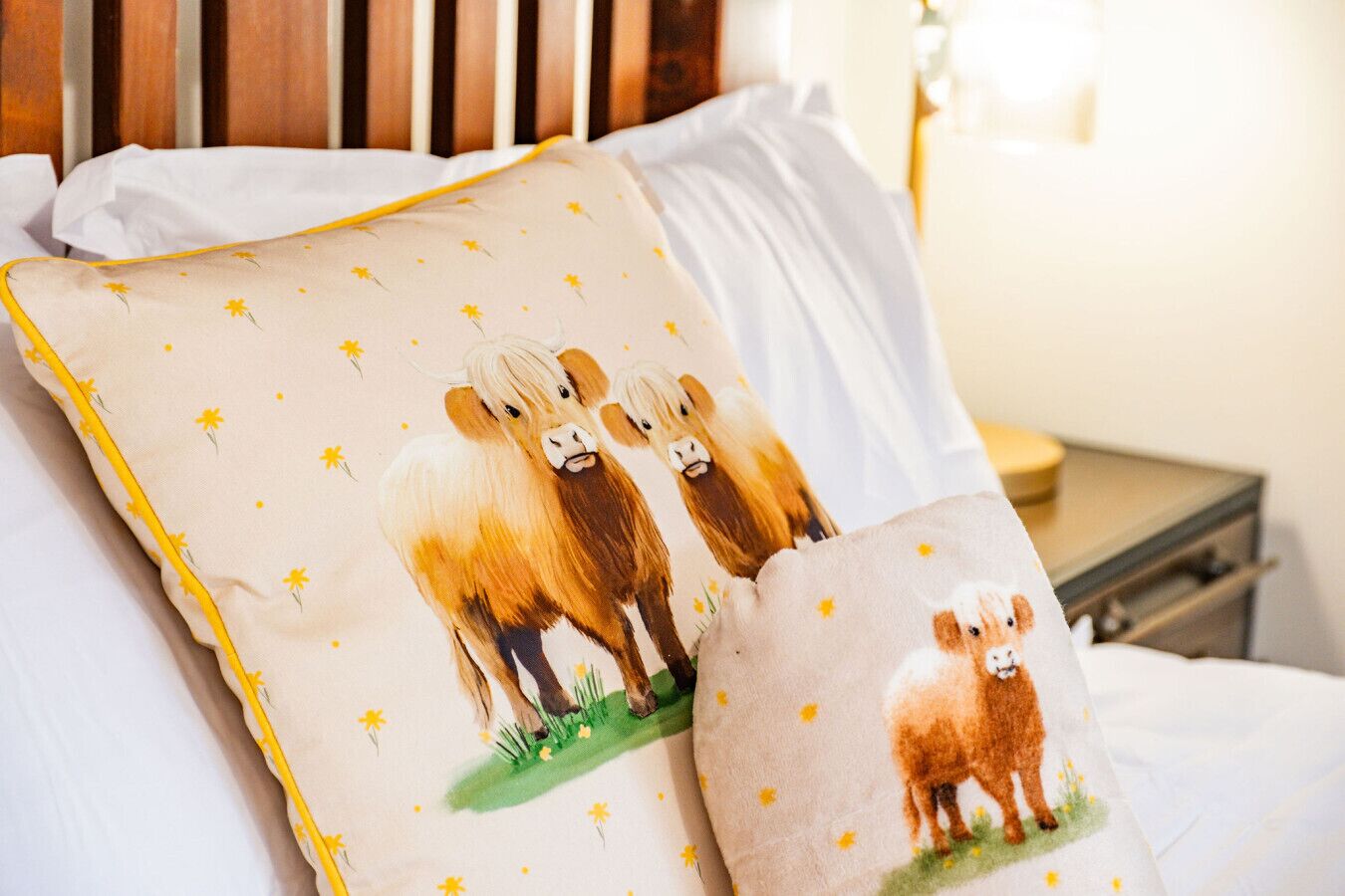 Un lit avec une literie blanche et deux coussins décoratifs ornés de motifs animaliers.