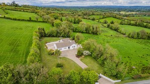 A white house with a fenced yard, surrounded by green fields and trees. - Hilltop View by Escape Ordinary (Lisbellaw, Enniskillen)