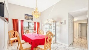 A dining area with a marble floor, a red tablecloth, and wooden chairs. - Waterfront 3BR 1Bath Furnished w/Gulf of America Access (NEW PORT RICHEY)