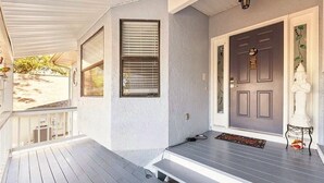 A porch with a dark door, a small step leading up to the entrance, and a white statue on the right. - Waterfront 3BR 1Bath Furnished w/Gulf of America Access (NEW PORT RICHEY)
