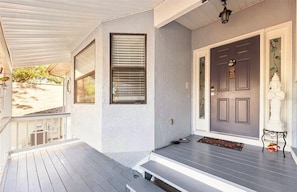 A porch with a dark door, a small step leading up to the entrance, and a white statue on the right. - Waterfront 3BR 1Bath Furnished w/Gulf of America Access (NEW PORT RICHEY)