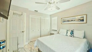 A bedroom with a bed, a ceiling fan, a door, and a framed picture on the wall. - Waterfront 3BR 1Bath Furnished w/Gulf of America Access (NEW PORT RICHEY)