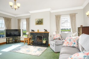 A living room with a fireplace, a television, and a sofa with floral cushions.