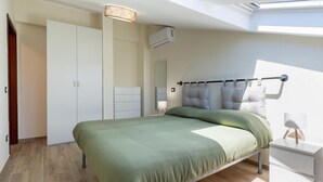 Une chambre à coucher comprenant un lit, une armoire, une table de chevet, une lampe et une lucarne.