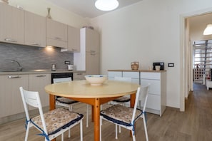 A modern kitchen with a round table, white chairs, and a bowl on the table.