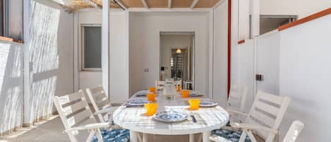 A dining area with a round table, white chairs, and blue cushions.