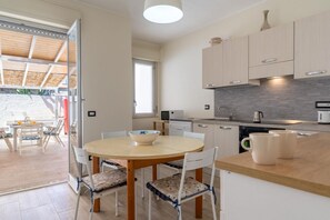 A modern kitchen with a dining area, wooden cabinets, and a view to the outside.