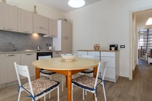 A modern kitchen with a round table, white chairs, and a bowl on the table.
