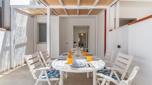 Un coin repas avec une table ronde, des chaises blanches et des coussins bleus.