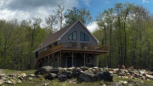 Une cabane dotée d’un balcon, entourée de rochers et d’arbres.
