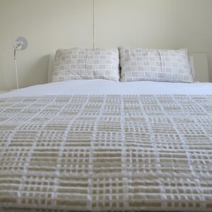 Ein Bett mit einem gemusterten Überwurf und zwei Kissen mit geometrischem Muster.