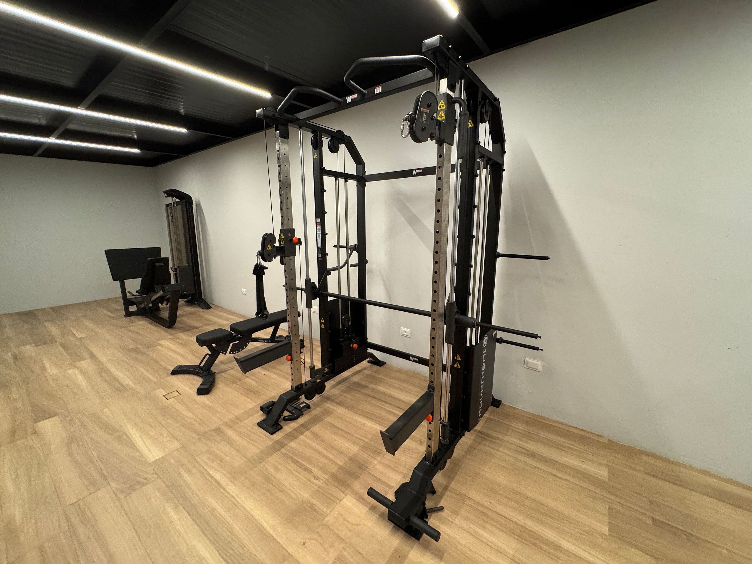 A gym with a squat rack, bench press, and weightlifting equipment.