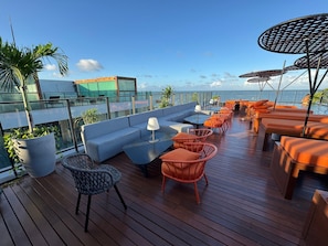 Un bar situé sur le toit, avec des places assises, une piscine et une vue sur l’océan.