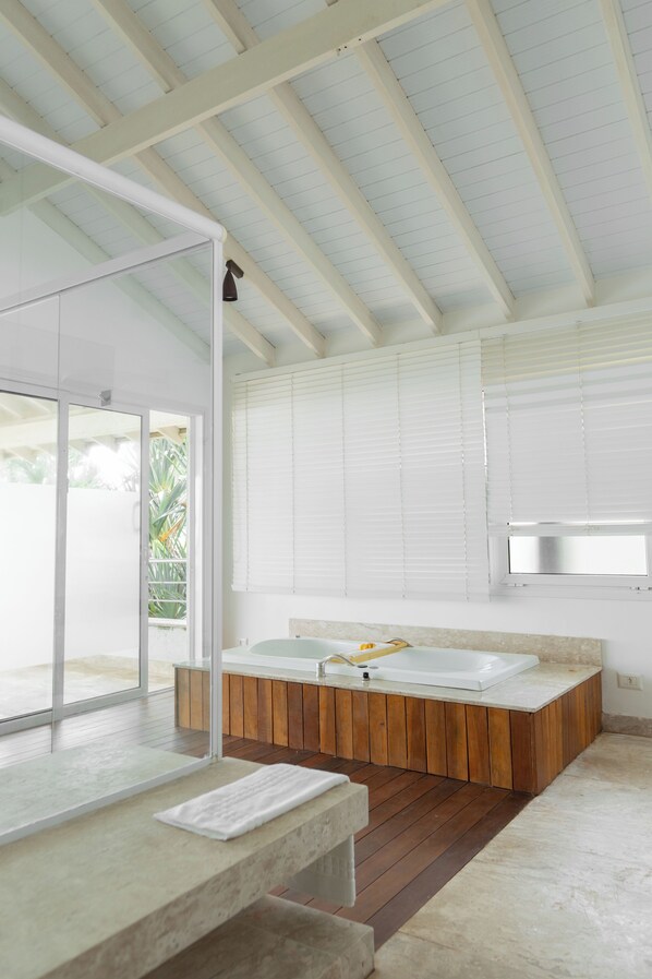 Un baño moderno con una bañera de madera, cabina de ducha de vidrio y un amplio ventanal.