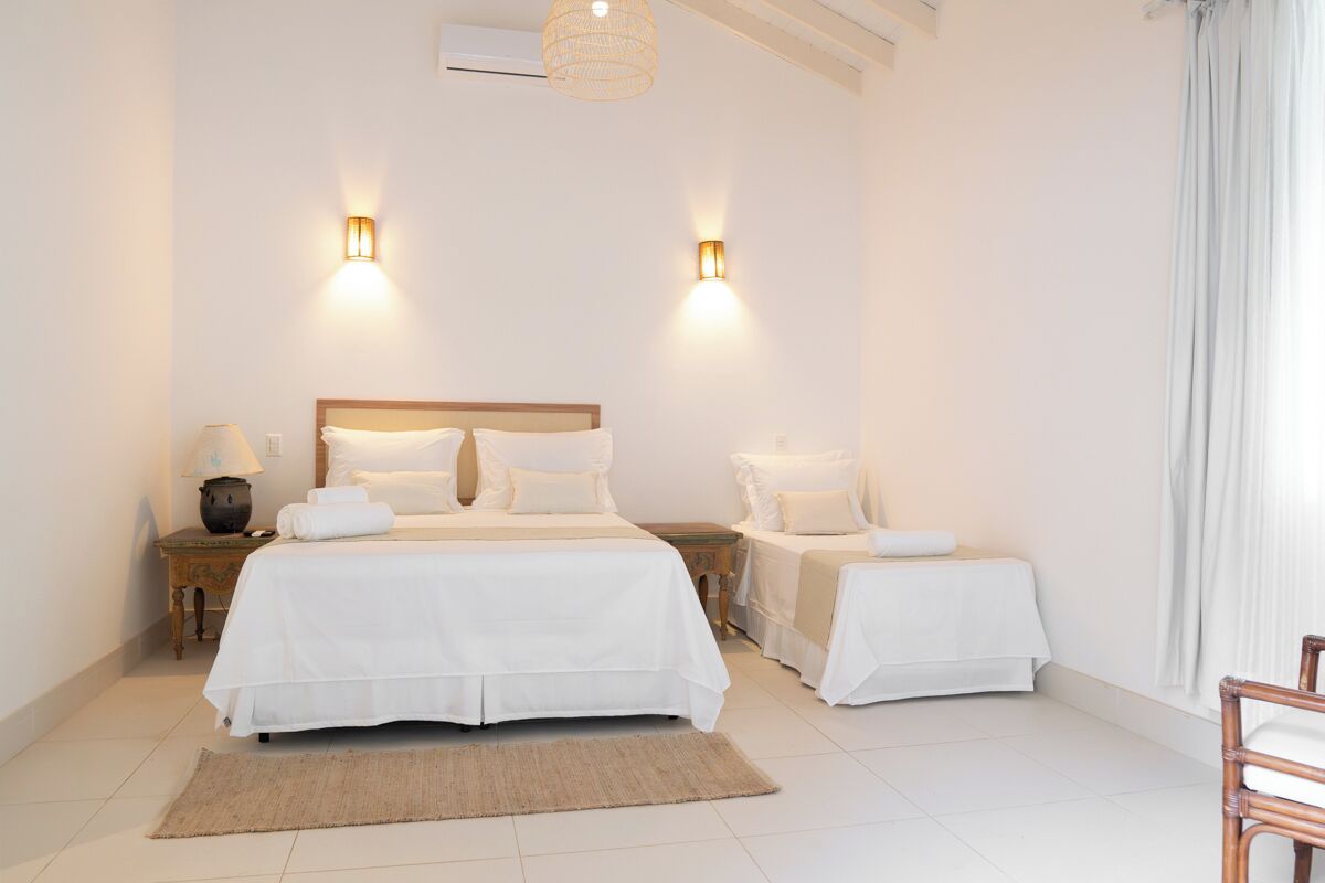 Une chambre à coucher avec un grand lit, deux tables de chevet, une lampe et un luminaire suspendu.