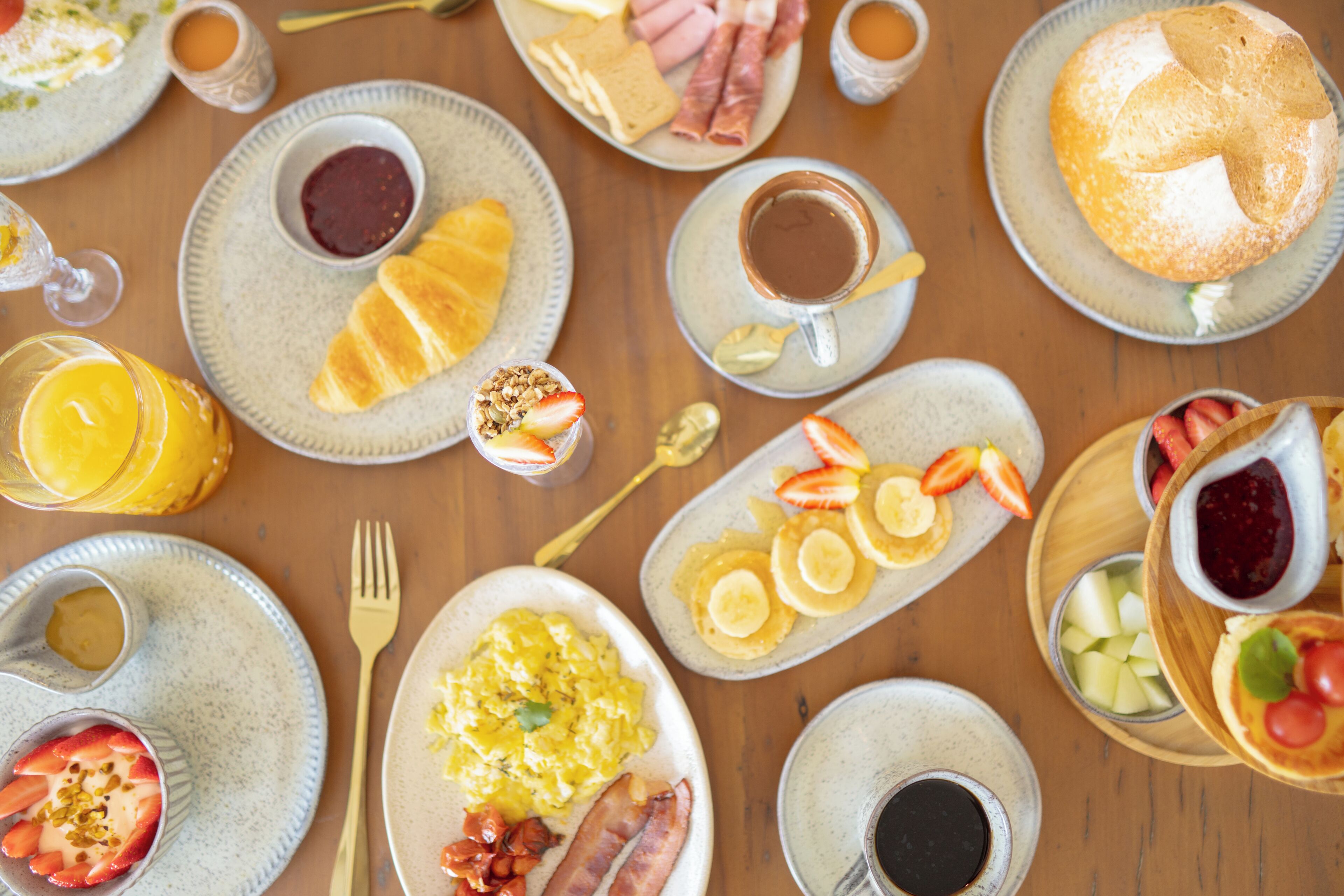 A breakfast setting with various dishes including eggs, bacon, toast, and fruit.
