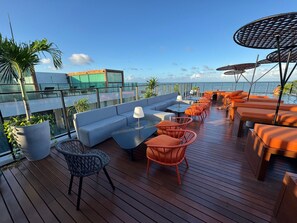 Een dakterras met zitplaatsen, een zwembad en uitzicht op de oceaan.
