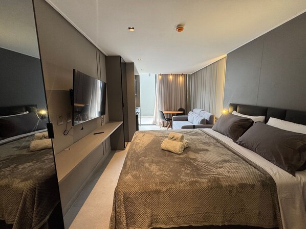 A modern hotel room with a large bed, a flat-screen TV mounted on the wall, and a small desk area. - First floor apartment with terrace at Acqua Tambau AQTX5 (João Pessoa)