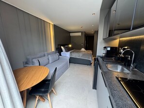 Une chambre d’hôtel moderne équipée d’un canapé, d’une table à manger, d’une kitchenette et d’un lit.