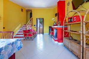 Ein Zimmer mit Treppe, Korbmöbeln, einer roten und weißen Farbgestaltung und einem Fliesenboden.