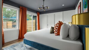 Ein Schlafzimmer mit einem großen Bett, einer Deckenleuchte und Blick ins Freie.